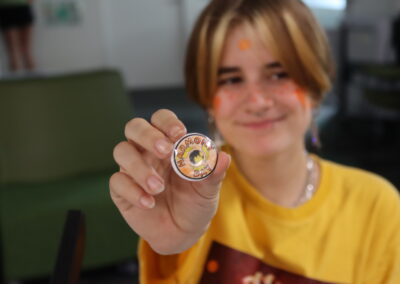 A student holding out the pin badge they made for Harmony Day