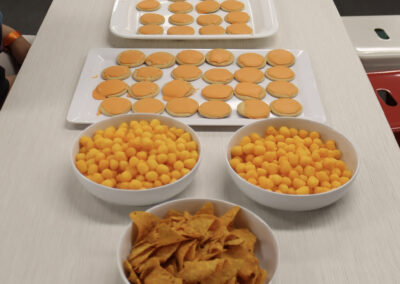 An assortment of plates on a table showcasing various orange food like chips and cookies